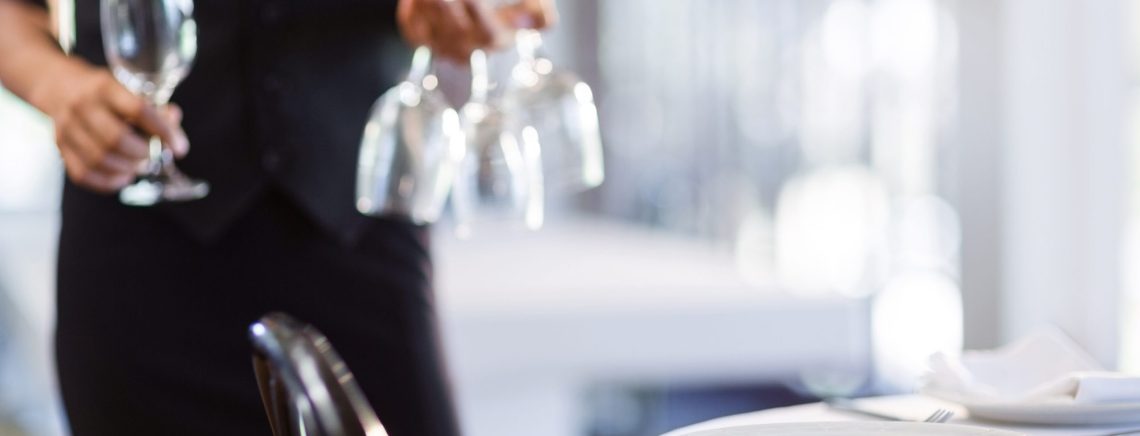 Mid section of waitress setting the table