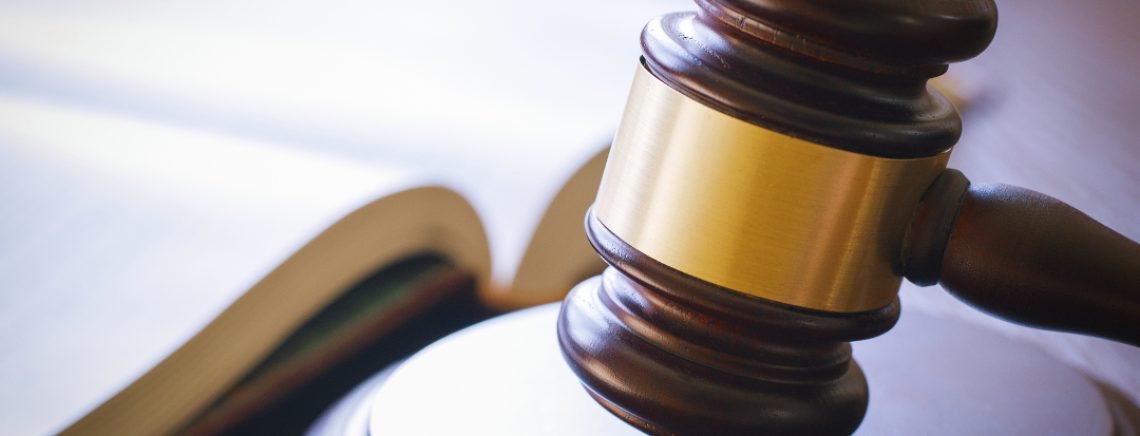 brown gavel and open book on a wooden table of the law in the courtroom
