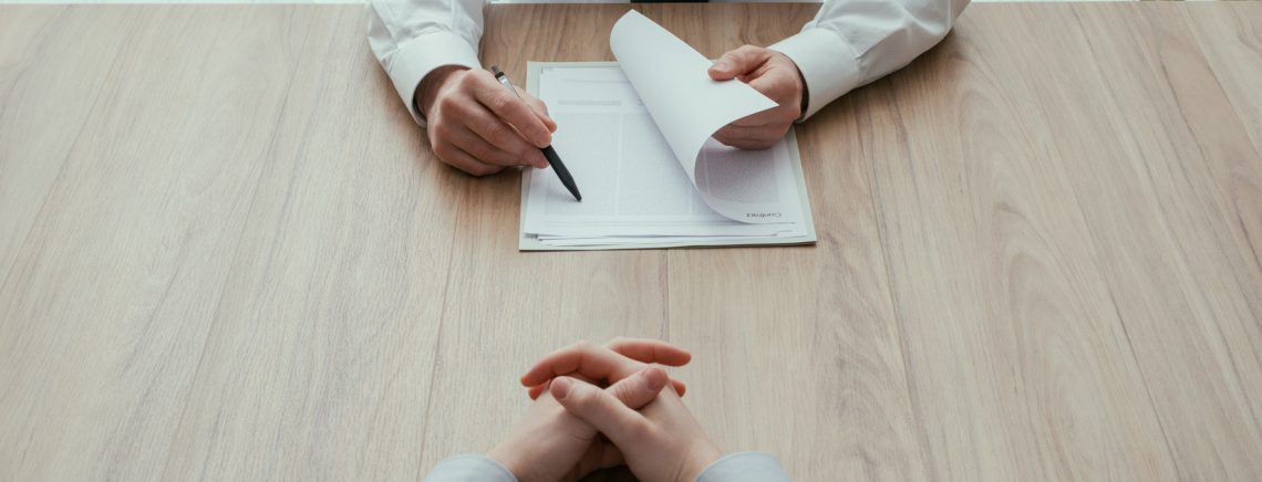 Examiner reading a resume during a job interview, employment and recruitment concept, point of view shot